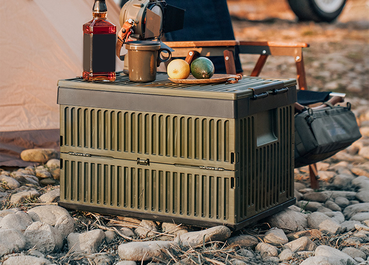Army green storage box used as a table in a rugged outdoor camping setup