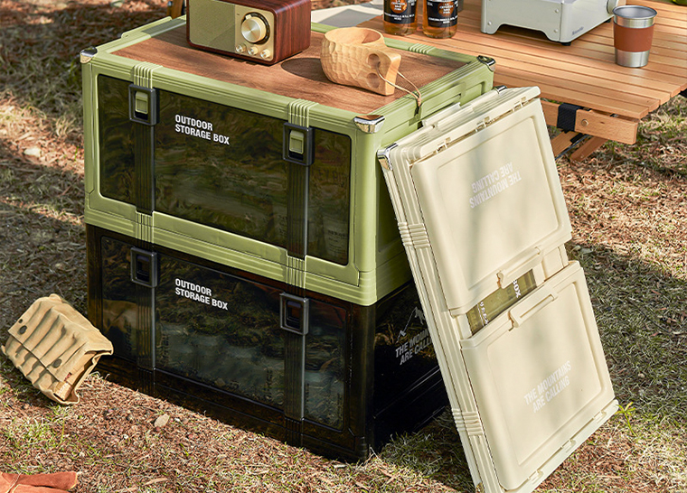 Double-decker outdoor storage boxes used as a side table with gear beside it.