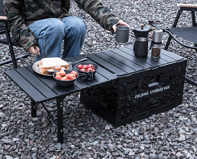 Black folding storage box used as a side table for serving food during outdoor camping