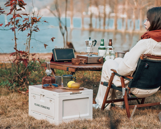 Beige folding storage box by the lake with bottles and fruits on top
