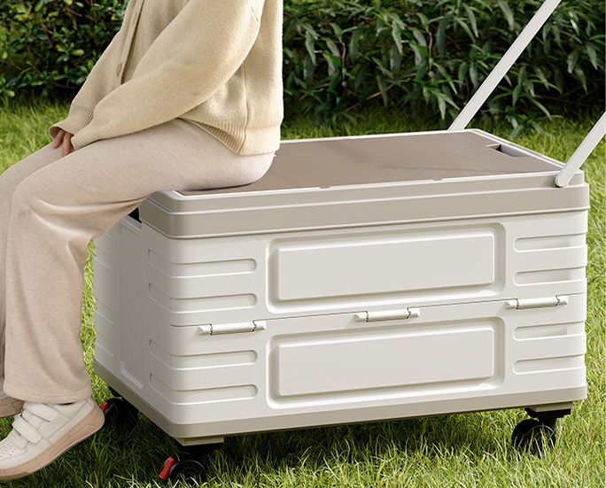 Person sitting on top of foldable storage box on grass