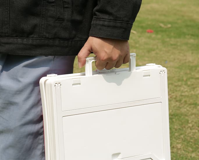 Hand carrying a folded white camping storage box with built-in handle
