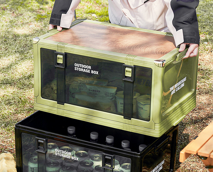 Green outdoor box with wood-pattern lid being placed on black box.