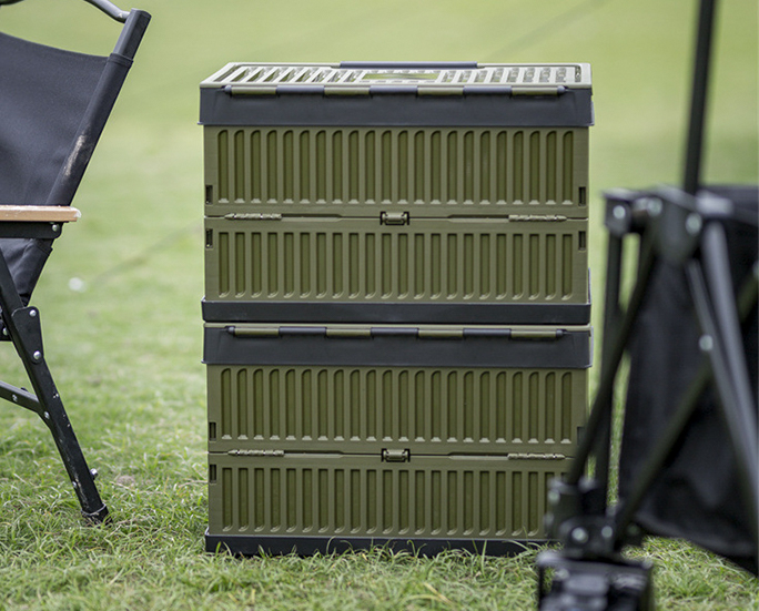 Two stackable army green foldable storage boxes on grass