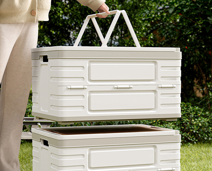 Person lifting stackable storage box with handle outdoors