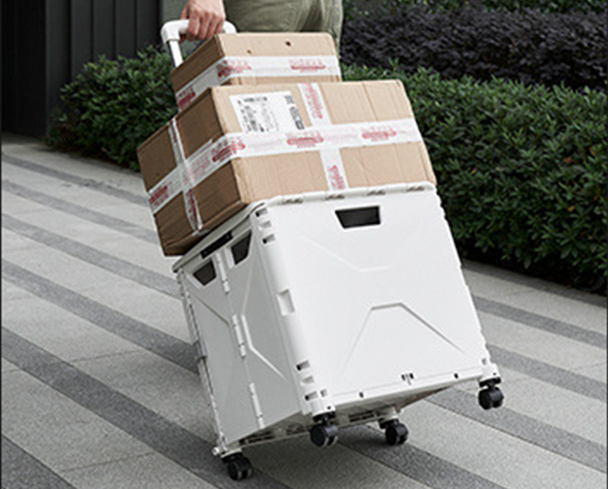 Man pulling a foldable storage box with cardboard packages on top