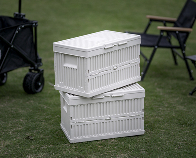 Two stackable white camping storage boxes on grass