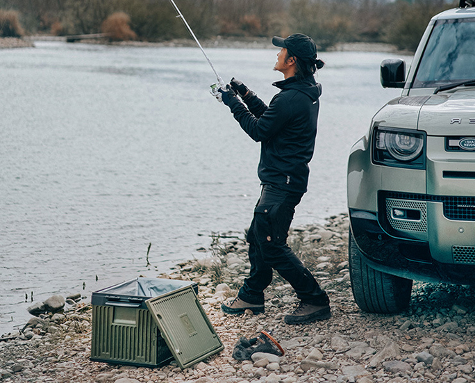 Man fishing beside an open military green storage box