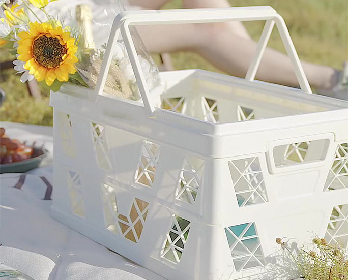 White folding picnic basket filled with sunflowers and wine