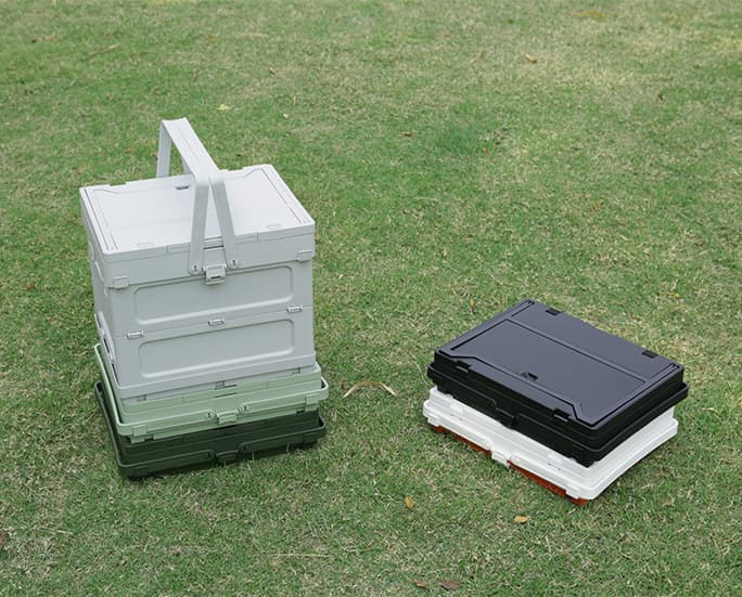 Foldable storage boxes with integrated lids shown in assembled and collapsed form on grass