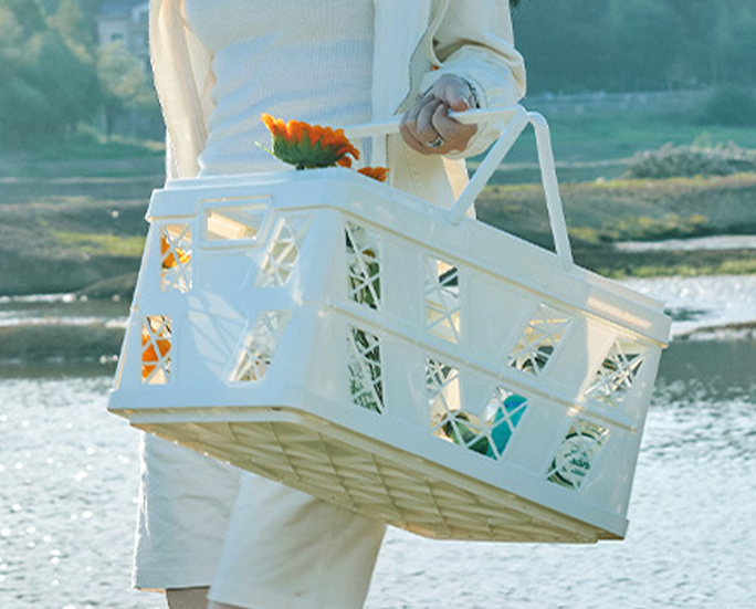Person sitting on white crate with wooden lid during picnic