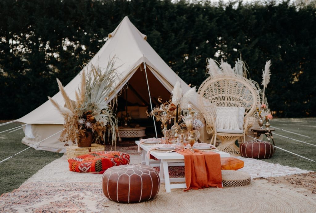 White or beige glamping tents Wooden tables,