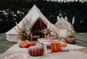 White or beige glamping tents Wooden tables,