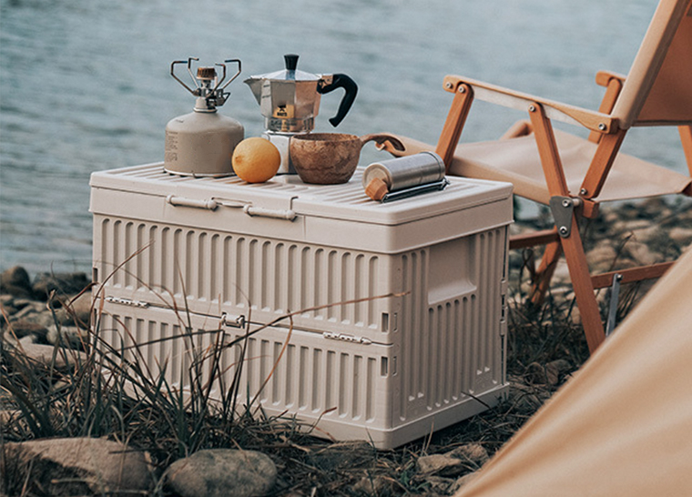 White folding storage box used as a camping table beside the lake