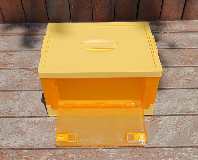 Yellow translucent folding box with front door open on wooden surface