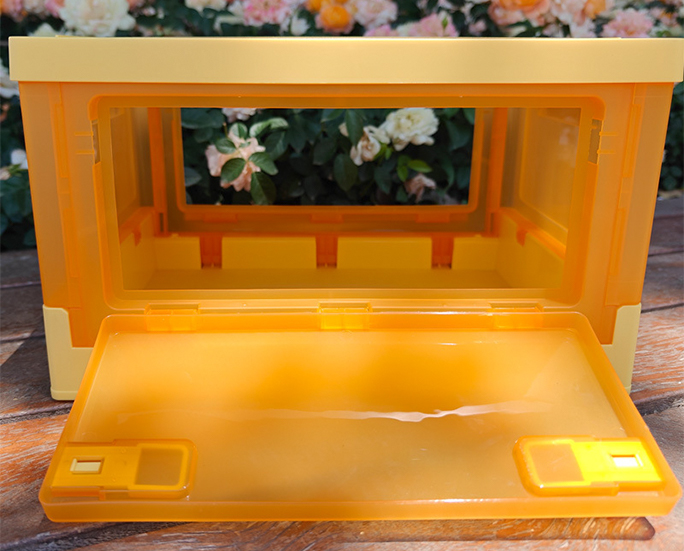 Yellow translucent crate with wide open front panel in floral background