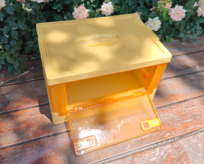 Top angle of yellow folding crate opened in garden setting