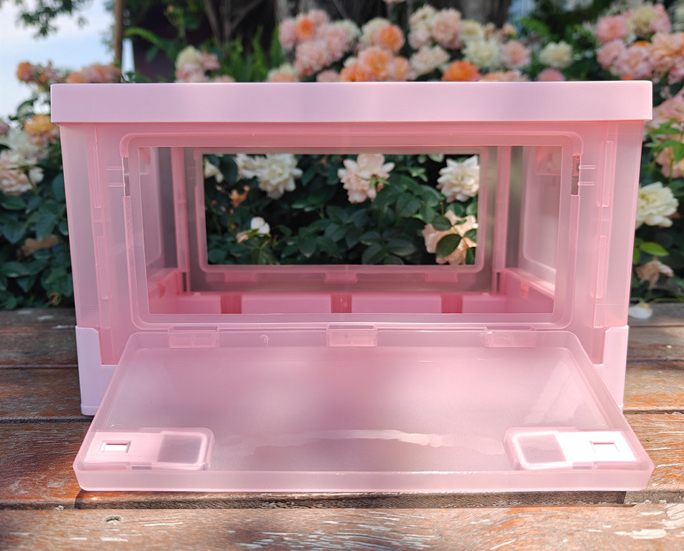 Pink folding crate with front door open in flower garden background