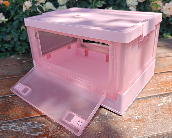 Outdoor photo of pink foldable box with translucent front opening door