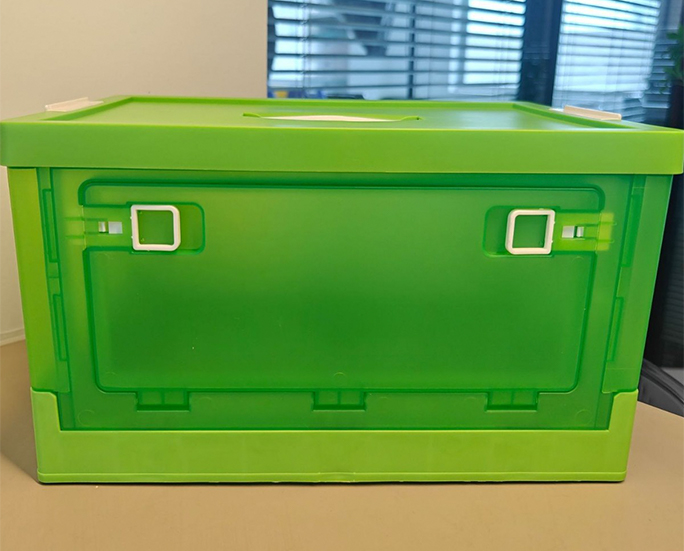 Front view of green plastic folding storage box with side locking handles