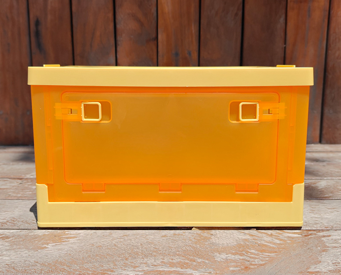 Front view of yellow plastic storage box with closed front door on wood background