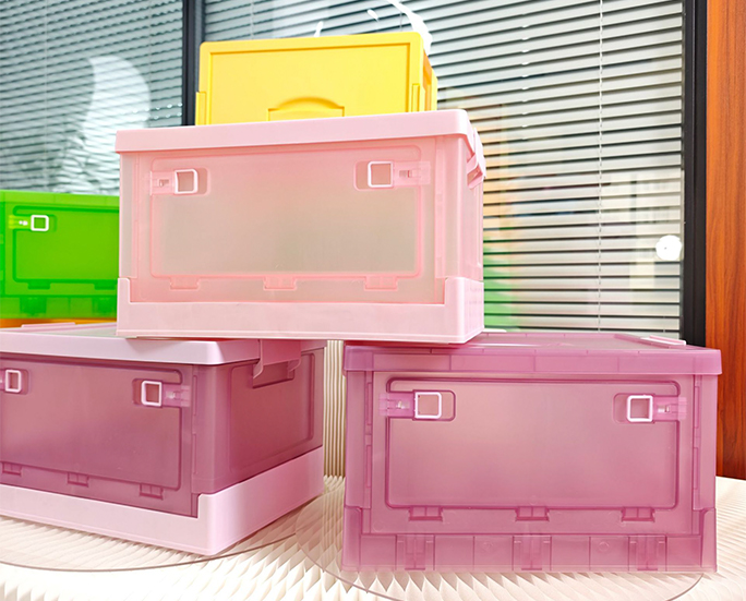 tacked foldable plastic storage bins in pink with yellow and green boxes in background