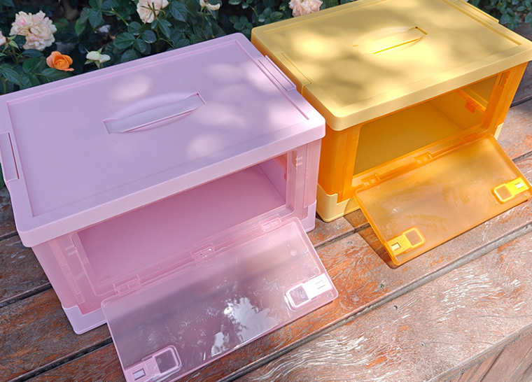 Pink and yellow folding storage bins open on wooden table in garden
