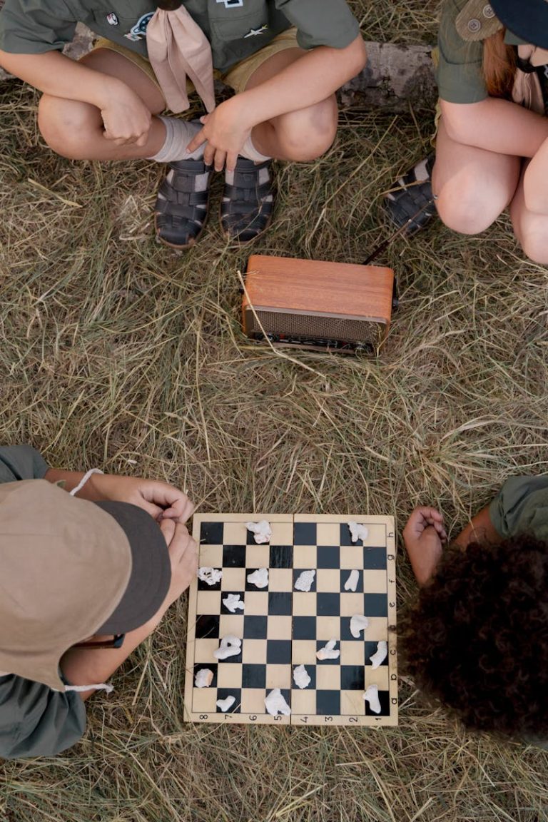 Overhead view of children playing chess surrounded by nature, capturing a fun camping moment.
