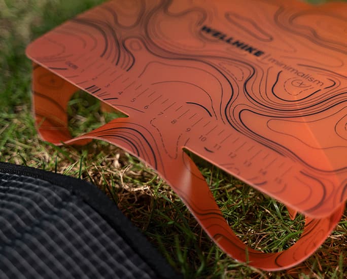 Primer plano de una mesa de camping plegable de color naranja con marcas de regla.