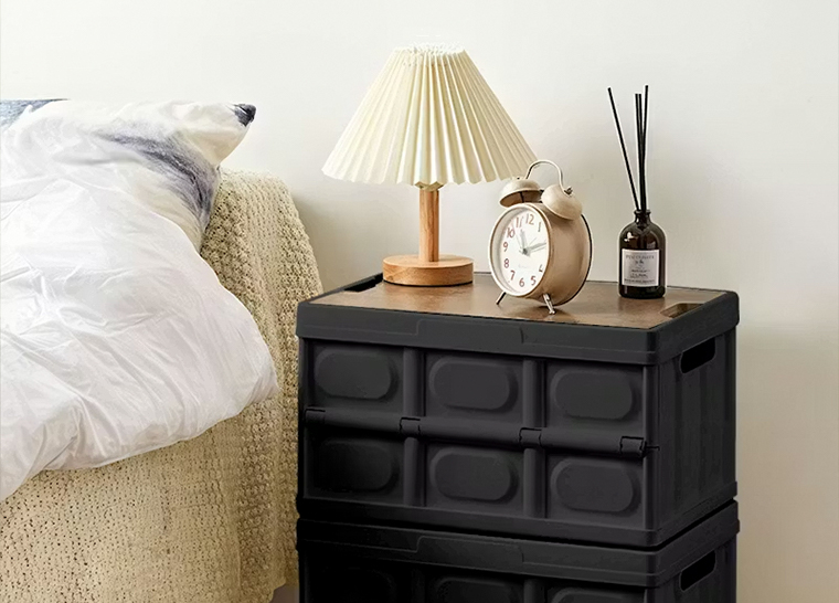 Caja de almacenamiento plegable con tapa de madera utilizada como mesita de noche.