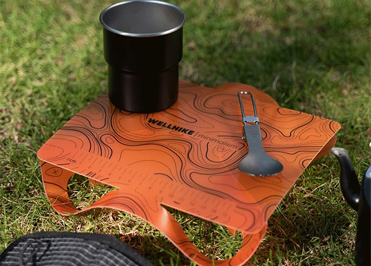 Mesa de camping plegable para uso al aire libre sobre césped.