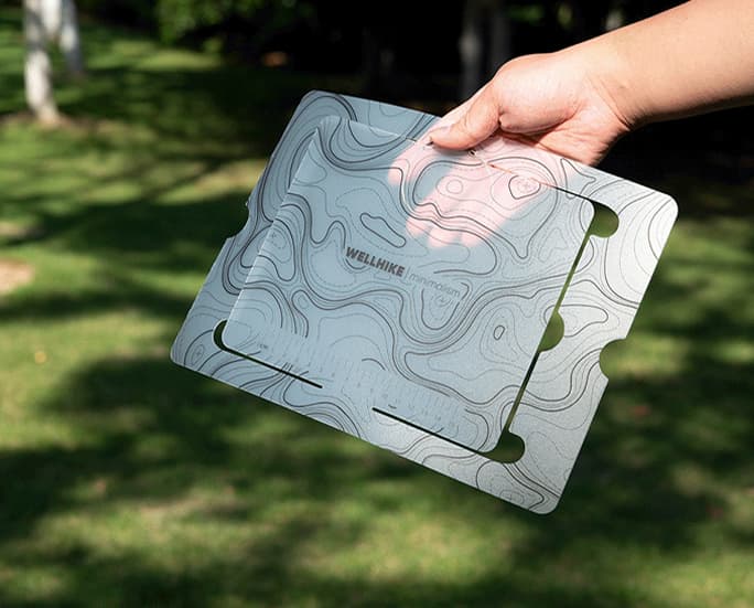 Hand carrying white topographic folding camp table outdoors